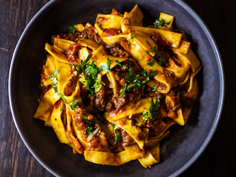 Pasta with sauce and herbs in a black bowl; illustrative stock photo, not Royal King's fettuccine.